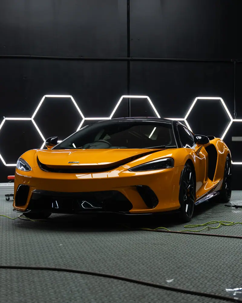 Orange McLaren GT with full PPF installation under hexagon studio lights