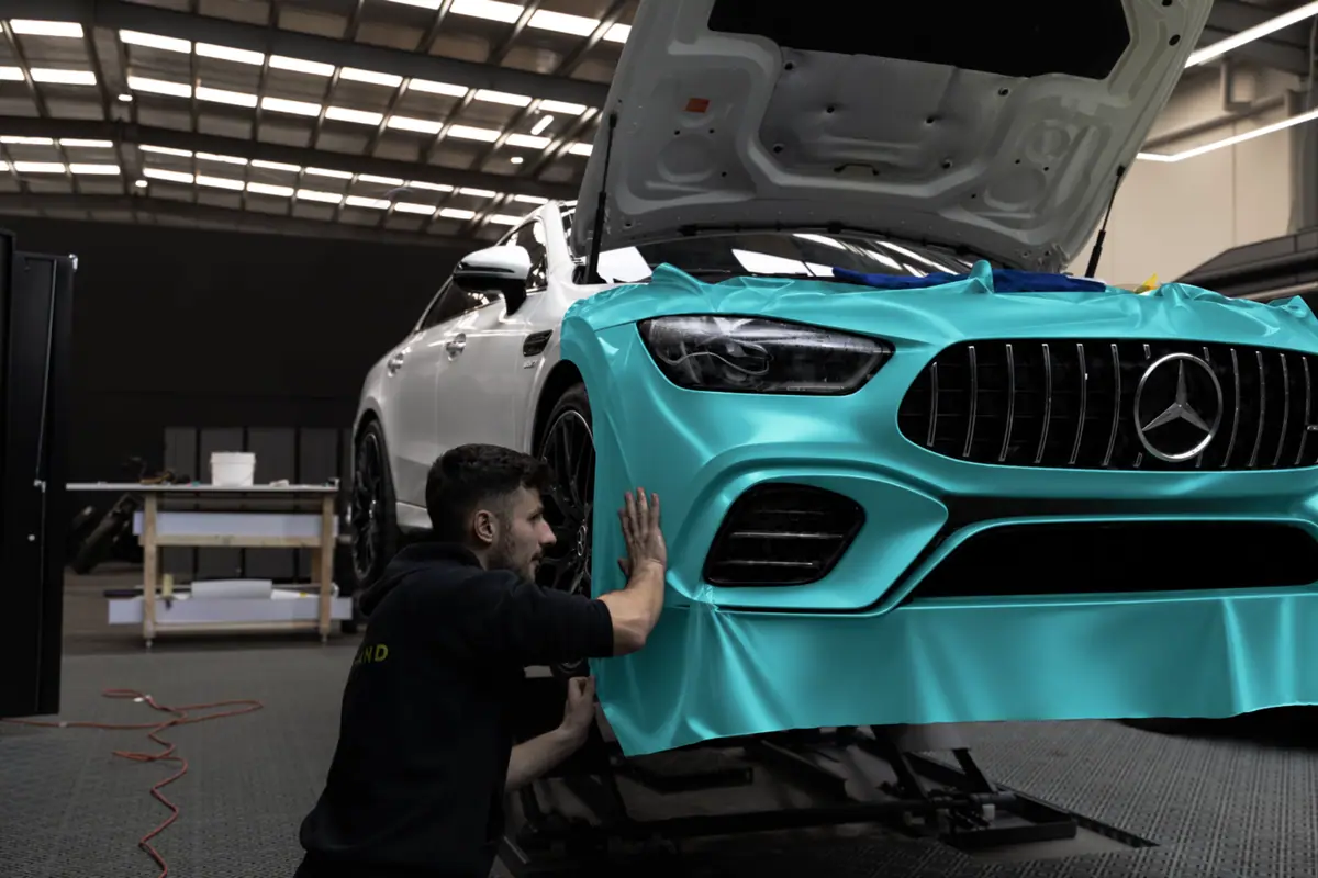 OzoneShield installer applying teal colour-change film to a Mercedes-AMG
